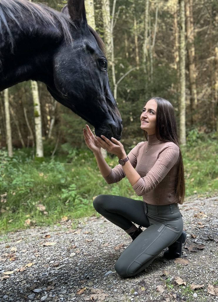 Michelle Wagner, Tierphysio- und Dorntherapeutin, mit einem Pferd in natürlicher Umgebung.